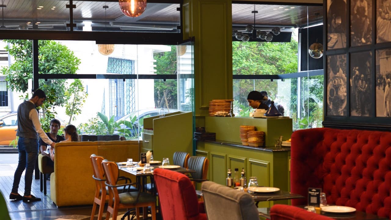 The Blacksmith dining room — sage-green bar, red velvet chesterfield banquettes and the artisan photo wall